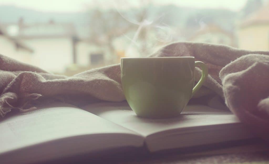steaming mug on book and blanket