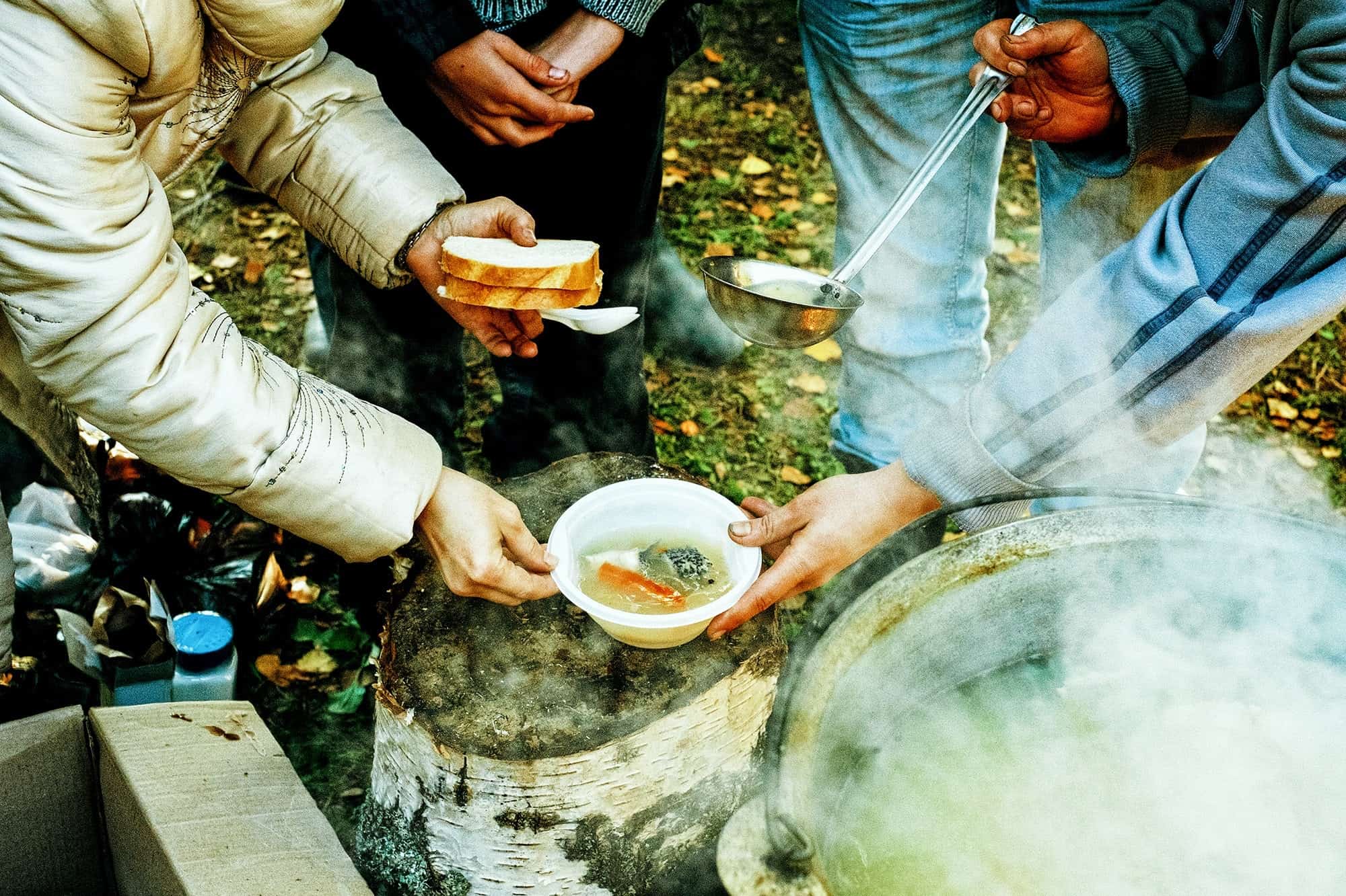 people gathering for hot soup and bread