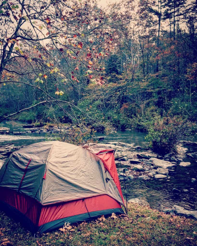 single camping tent next to water in the woods fun date night idea