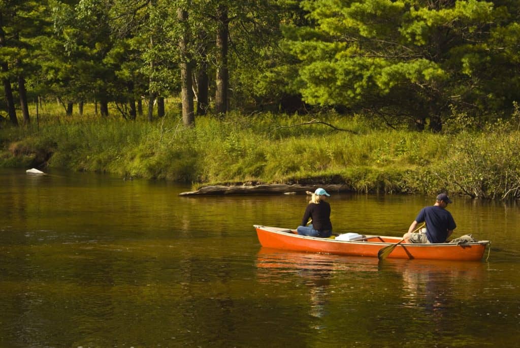 couple paddling a canoe on a creek through the woods fun date night idea