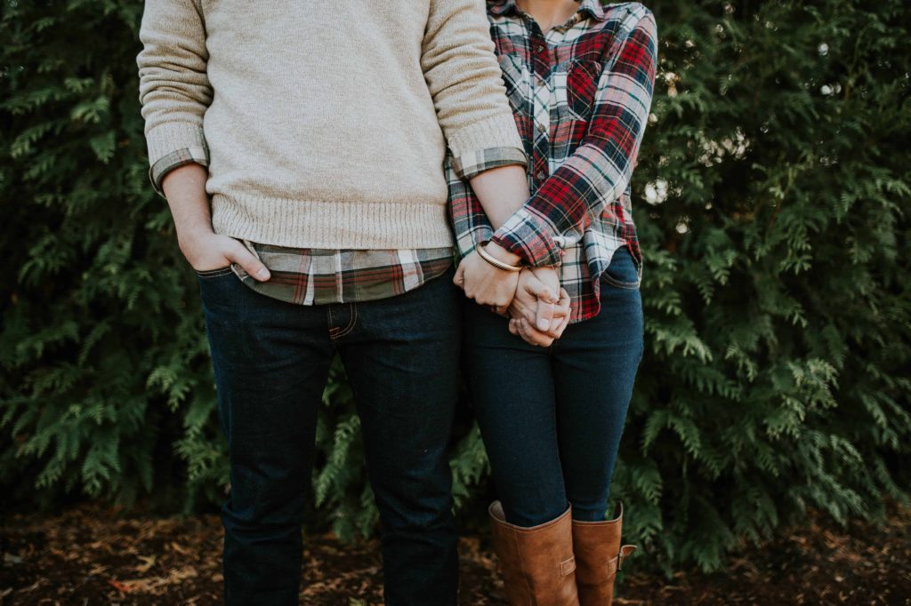 young couple in fall attire standing close together holding hands
