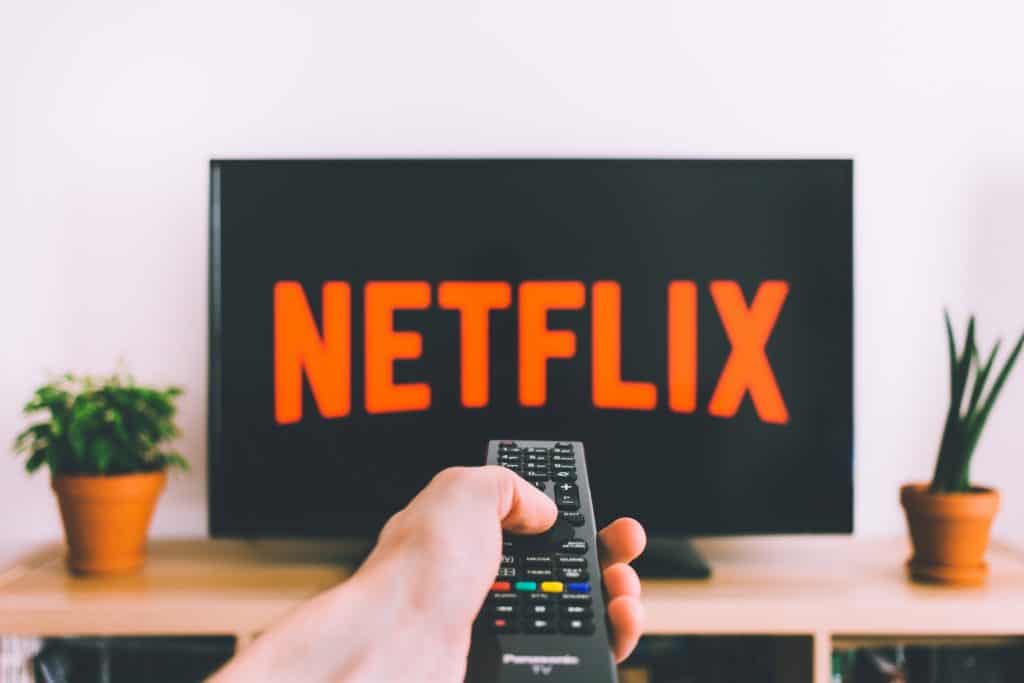 pointing remote at a tv screen that says Netflix in large letters