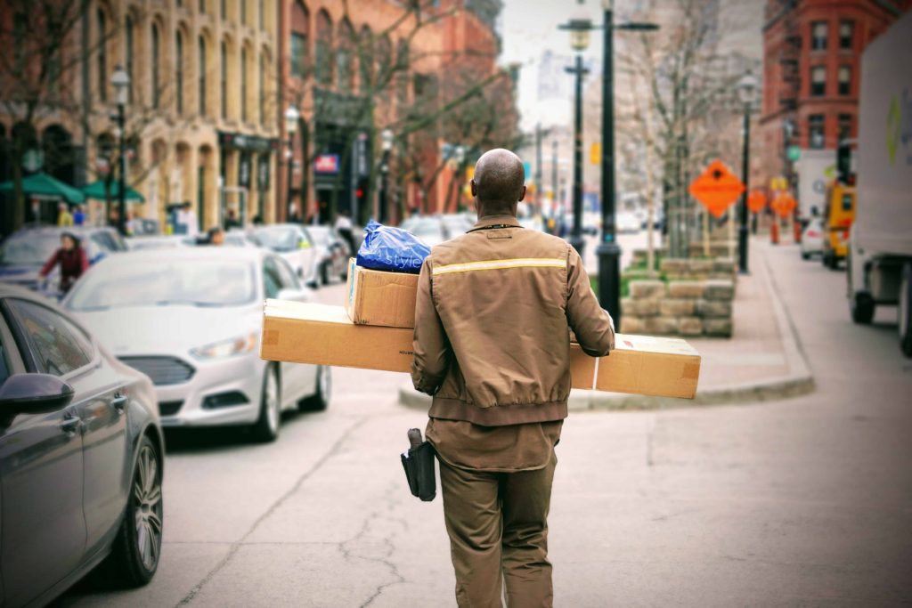delivery man carrying large boxes down city street