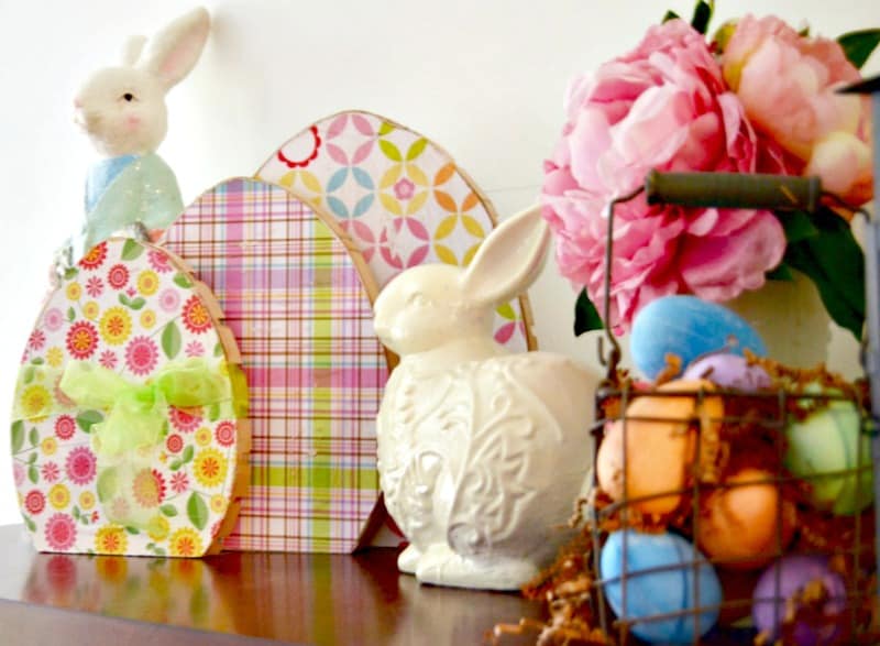 large wooden decorated eggs on mantel with bunny statue and basket of easter eggs diy easter decoration