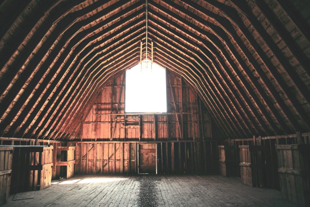 interior of empty wooden barn with bright sunlight streaming in the open hay loft door showing a perfect space to rent a barn for storage